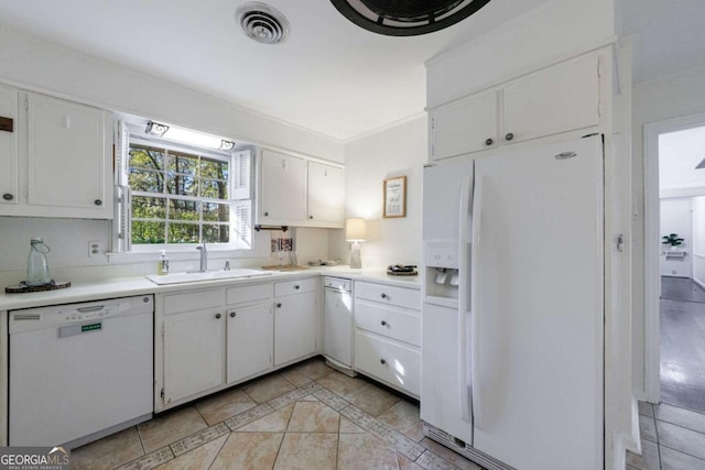 kitchen featuring sink, white cabinets, light tile patterned flooring, and white appliances