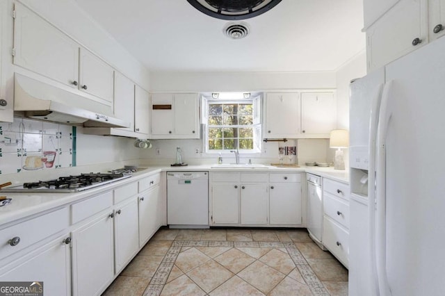 kitchen with decorative backsplash, white appliances, sink, light tile patterned floors, and white cabinets