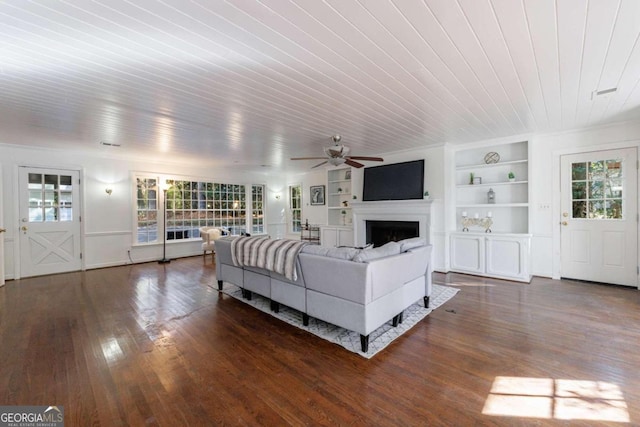 living room with plenty of natural light, dark hardwood / wood-style floors, ceiling fan, and built in shelves