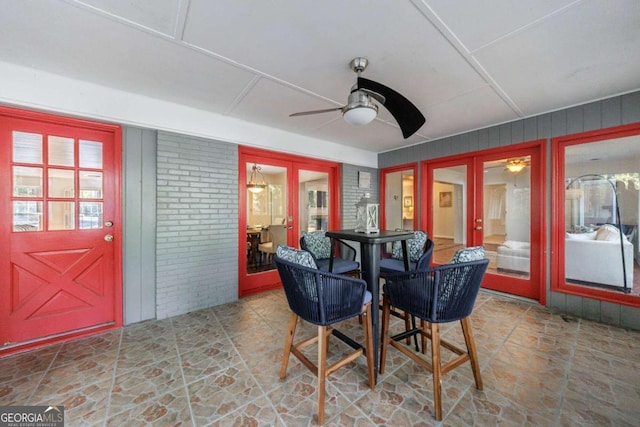 dining space with french doors, ceiling fan, and brick wall