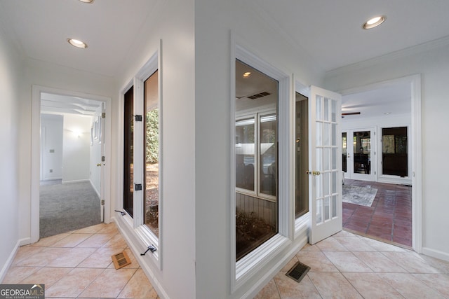 hallway with crown molding, light carpet, and french doors