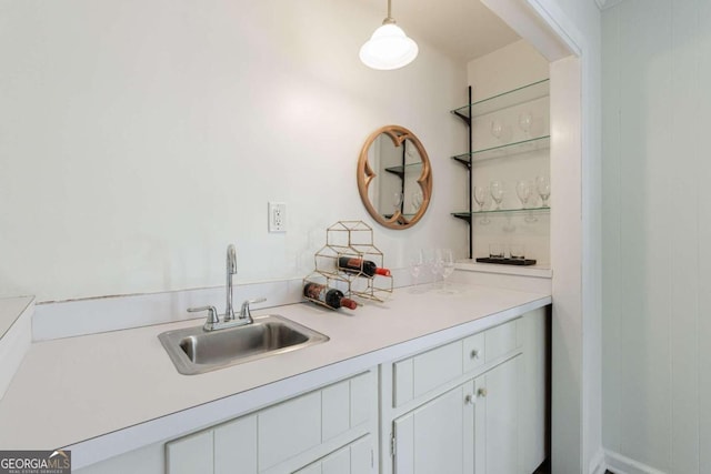 bar with white cabinetry, hanging light fixtures, and sink