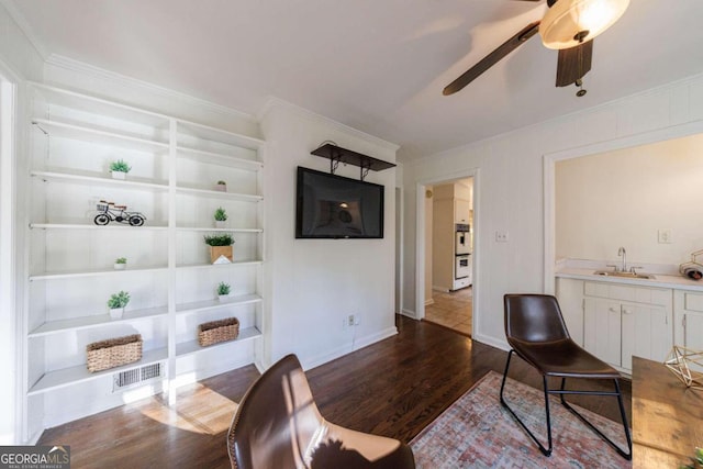 living room with ornamental molding, ceiling fan, sink, wood-type flooring, and built in features