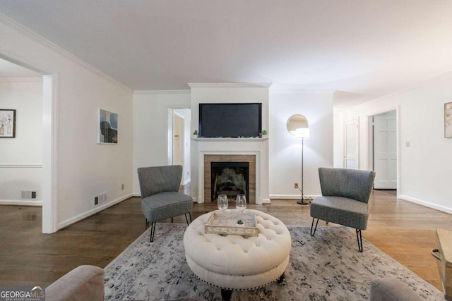 living room featuring a fireplace, wood-type flooring, and crown molding