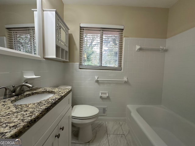 bathroom featuring a bathing tub, vanity, tile walls, and toilet