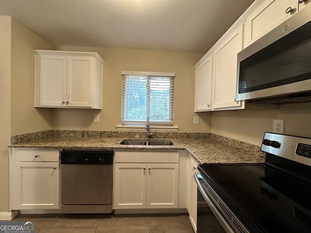 kitchen featuring light stone countertops, white cabinetry, sink, stainless steel appliances, and light tile patterned floors