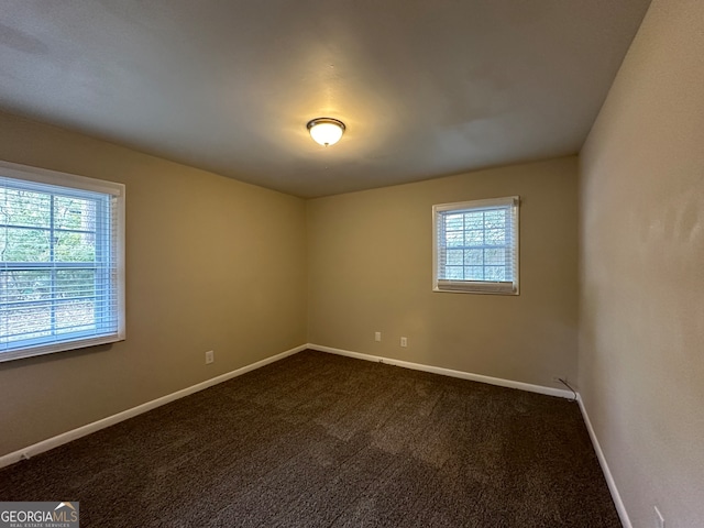 empty room featuring dark carpet and a wealth of natural light