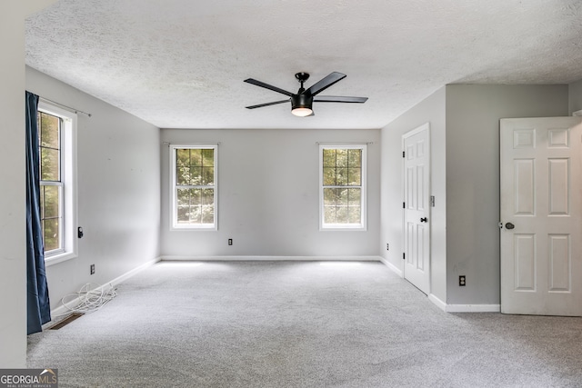 spare room featuring ceiling fan, a healthy amount of sunlight, light colored carpet, and a textured ceiling