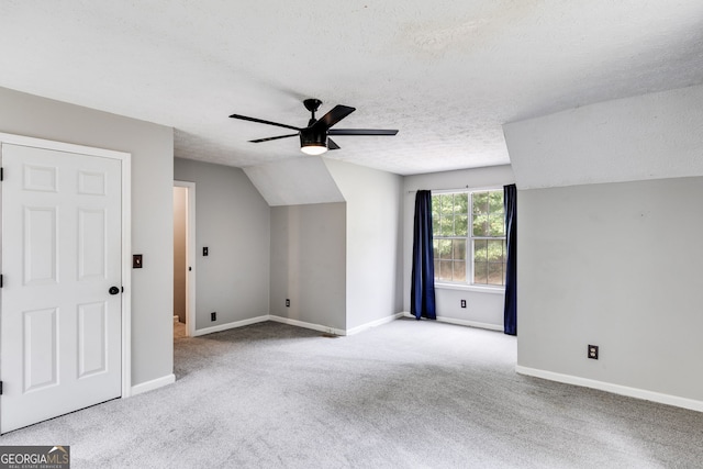 additional living space featuring a textured ceiling, ceiling fan, lofted ceiling, and light carpet