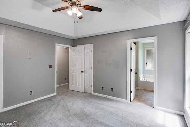 unfurnished bedroom with ceiling fan, light carpet, and a textured ceiling