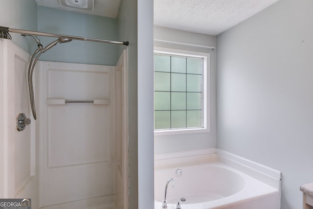 bathroom featuring plus walk in shower and a textured ceiling