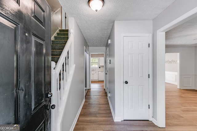 hall with a textured ceiling and hardwood / wood-style flooring