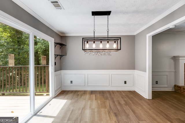 unfurnished dining area featuring crown molding, light hardwood / wood-style floors, and a textured ceiling