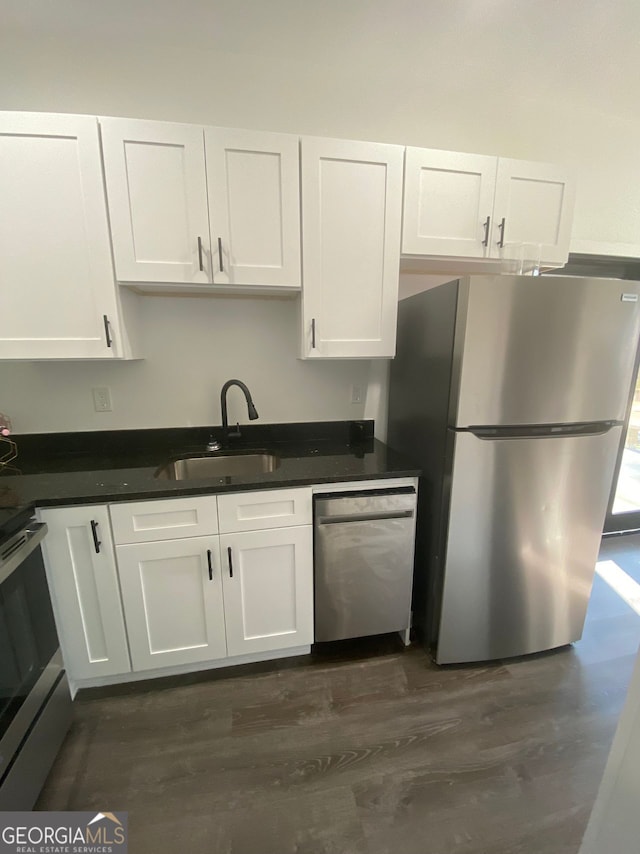 kitchen featuring appliances with stainless steel finishes, dark hardwood / wood-style flooring, white cabinetry, and sink