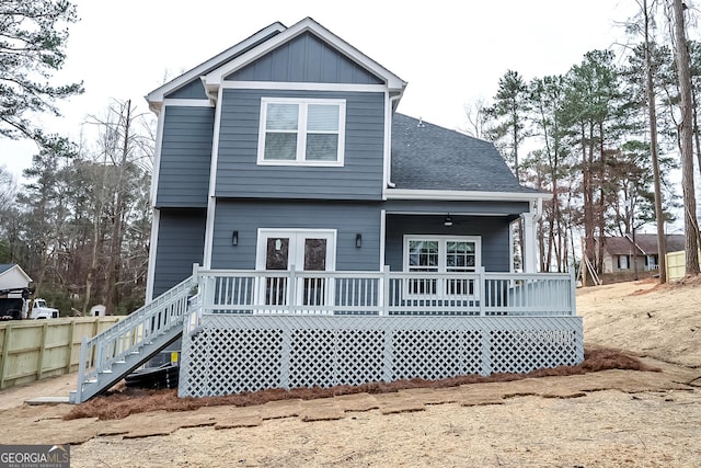 rear view of property featuring a wooden deck, fence, board and batten siding, and roof with shingles