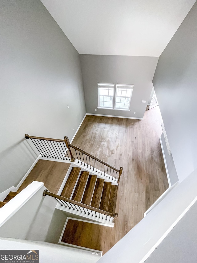 stairs featuring baseboards, vaulted ceiling, and wood finished floors