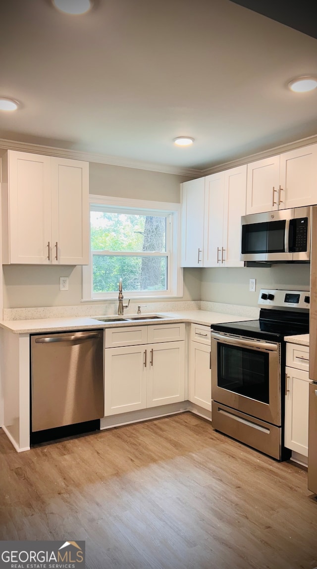 kitchen with light wood-type flooring, white cabinetry, and appliances with stainless steel finishes