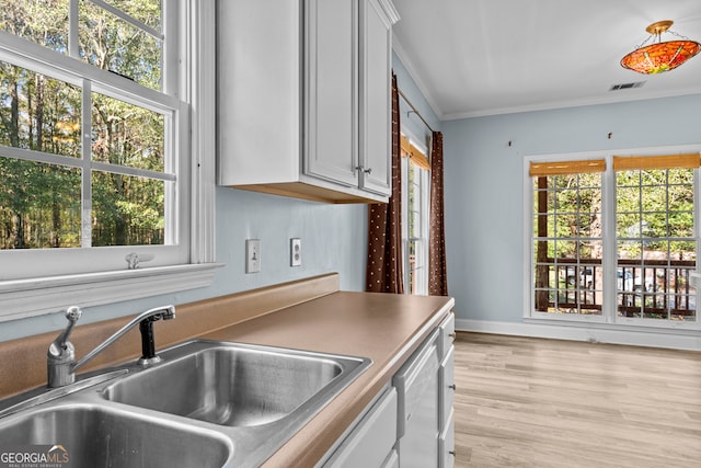 kitchen featuring white cabinetry, sink, light hardwood / wood-style floors, and ornamental molding