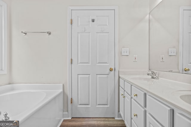 bathroom featuring hardwood / wood-style floors, vanity, and a tub to relax in