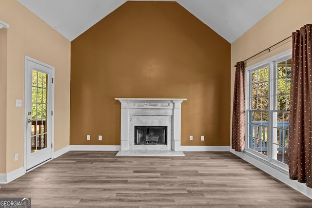 unfurnished living room with a fireplace, high vaulted ceiling, and light hardwood / wood-style flooring