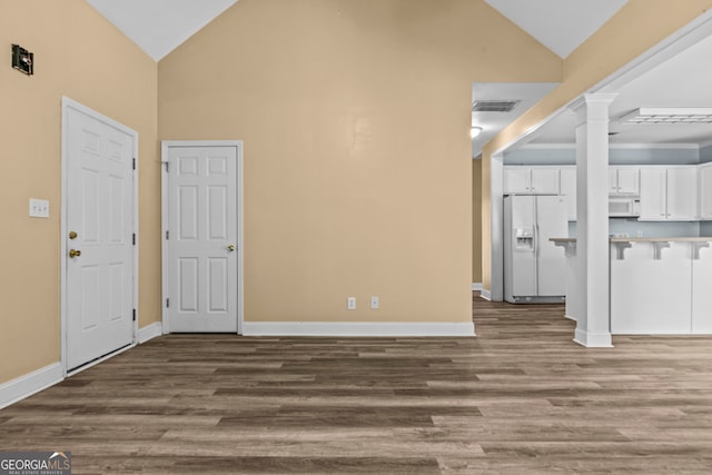 interior space featuring hardwood / wood-style floors, decorative columns, and high vaulted ceiling