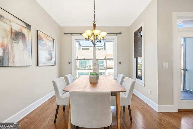 dining area with ornamental molding, a chandelier, and hardwood / wood-style flooring