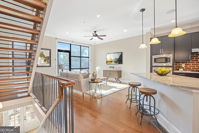 living room featuring light hardwood / wood-style flooring, ceiling fan, and crown molding