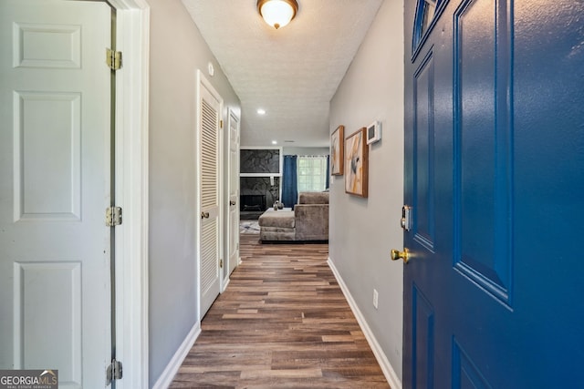 hallway with a textured ceiling and dark hardwood / wood-style floors