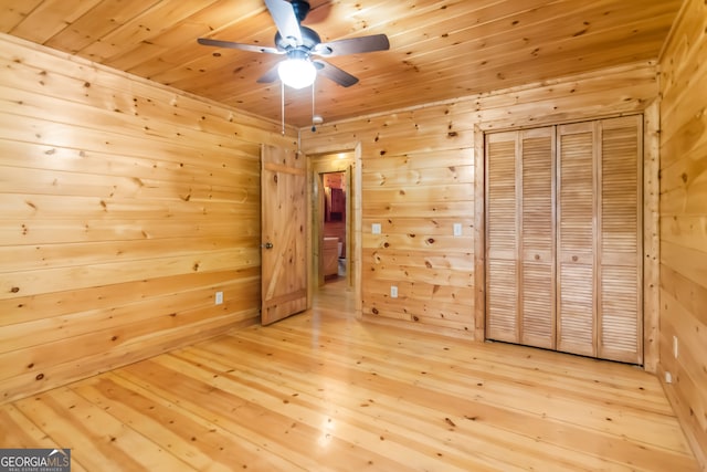 unfurnished bedroom with wood-type flooring, wooden ceiling, a closet, and wooden walls