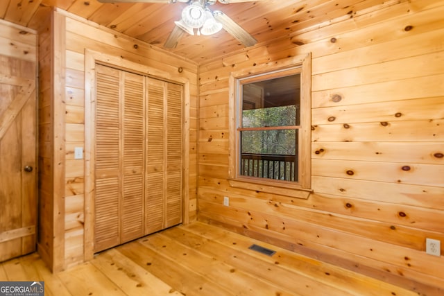 unfurnished bedroom featuring hardwood / wood-style flooring, a closet, wood walls, and wood ceiling