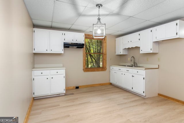 kitchen featuring a drop ceiling, sink, hanging light fixtures, light hardwood / wood-style floors, and white cabinetry