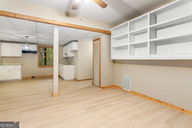 basement with a paneled ceiling, ceiling fan, light hardwood / wood-style flooring, and sink