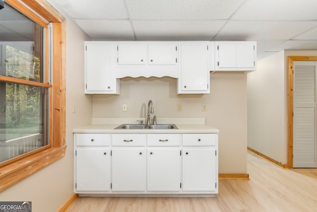 kitchen featuring white cabinetry, sink, light hardwood / wood-style floors, and a drop ceiling