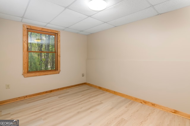 spare room featuring a drop ceiling and light wood-type flooring