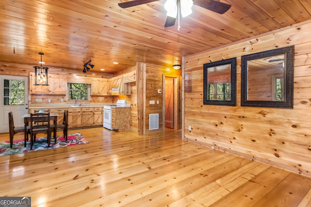 interior space with wood ceiling, white range oven, wooden walls, sink, and light hardwood / wood-style floors