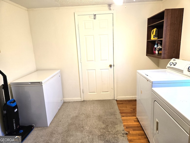 clothes washing area featuring hardwood / wood-style floors, washer and dryer, a textured ceiling, and ornamental molding