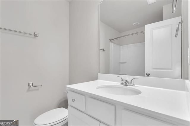 bathroom featuring vanity, toilet, and a shower