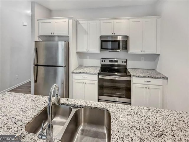 kitchen featuring dark wood-type flooring, sink, light stone countertops, appliances with stainless steel finishes, and white cabinetry