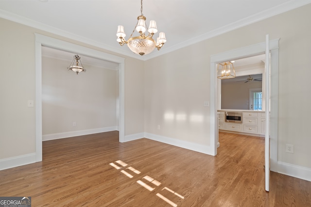 unfurnished dining area with hardwood / wood-style flooring, ceiling fan with notable chandelier, and ornamental molding