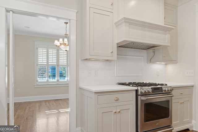 kitchen with an inviting chandelier, tasteful backsplash, high end stove, crown molding, and light hardwood / wood-style floors