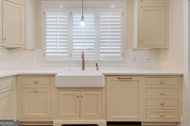 kitchen featuring tasteful backsplash, sink, and cream cabinetry