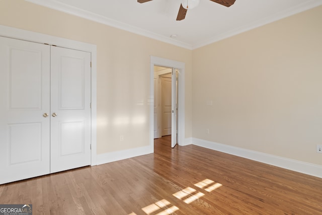 unfurnished bedroom with a closet, hardwood / wood-style flooring, ceiling fan, and crown molding