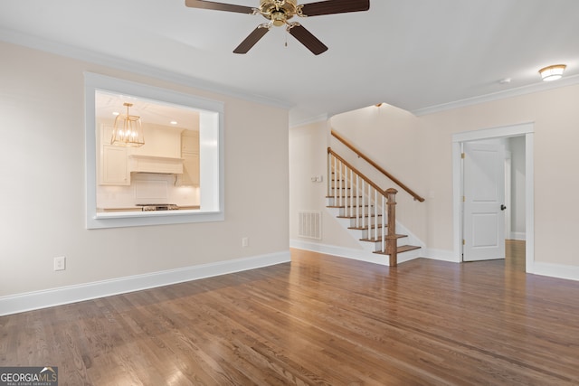 unfurnished living room featuring crown molding, dark wood-type flooring, and ceiling fan with notable chandelier