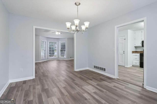 unfurnished dining area with light hardwood / wood-style flooring, ceiling fan with notable chandelier, and a textured ceiling