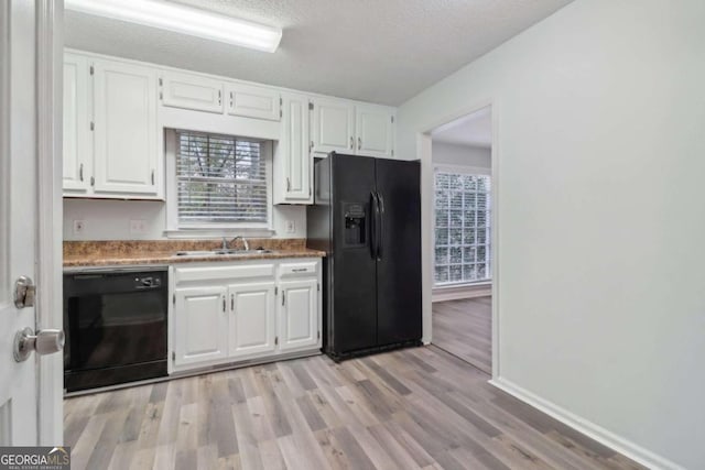 kitchen with white cabinets, light hardwood / wood-style flooring, and black appliances