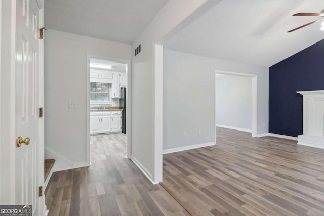 unfurnished living room featuring ceiling fan, light wood-type flooring, and a brick fireplace