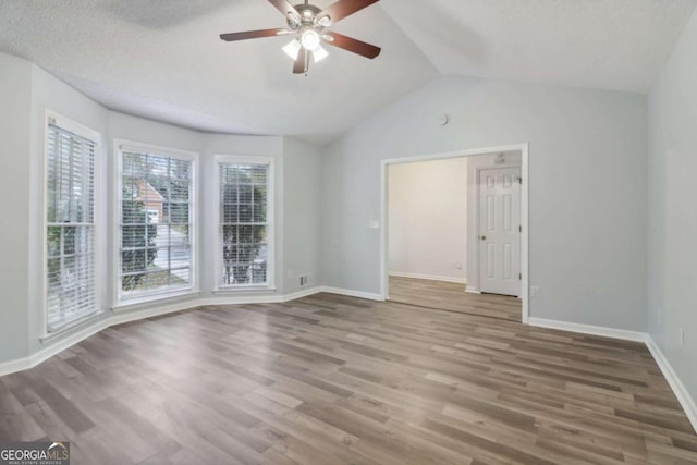 spare room with a textured ceiling, ceiling fan, wood-type flooring, and vaulted ceiling