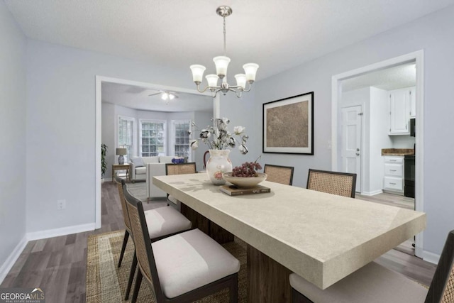 dining room featuring ceiling fan with notable chandelier and wood-type flooring