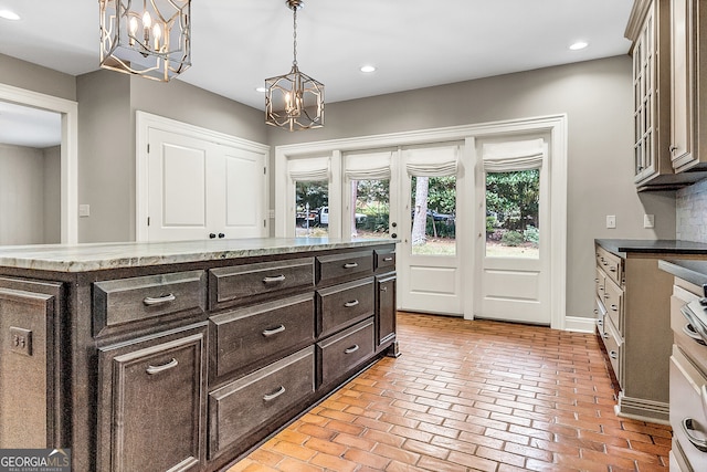 kitchen with dark brown cabinets, an inviting chandelier, decorative light fixtures, and a kitchen island