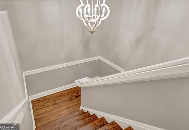 stairs with a chandelier and hardwood / wood-style floors